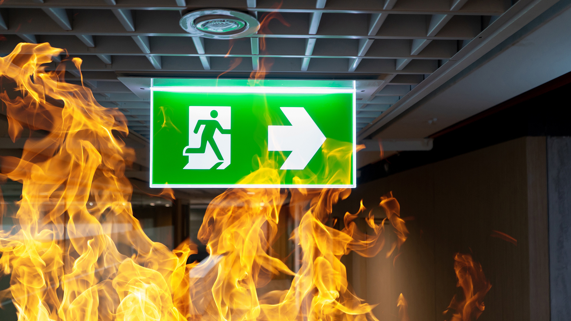 Emergency Runningman Exit Light set in a background of Flames