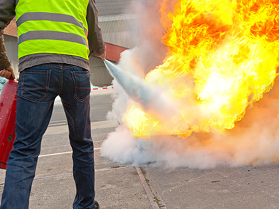 Portable fire extinguisher being used to put out a spot fire by team member