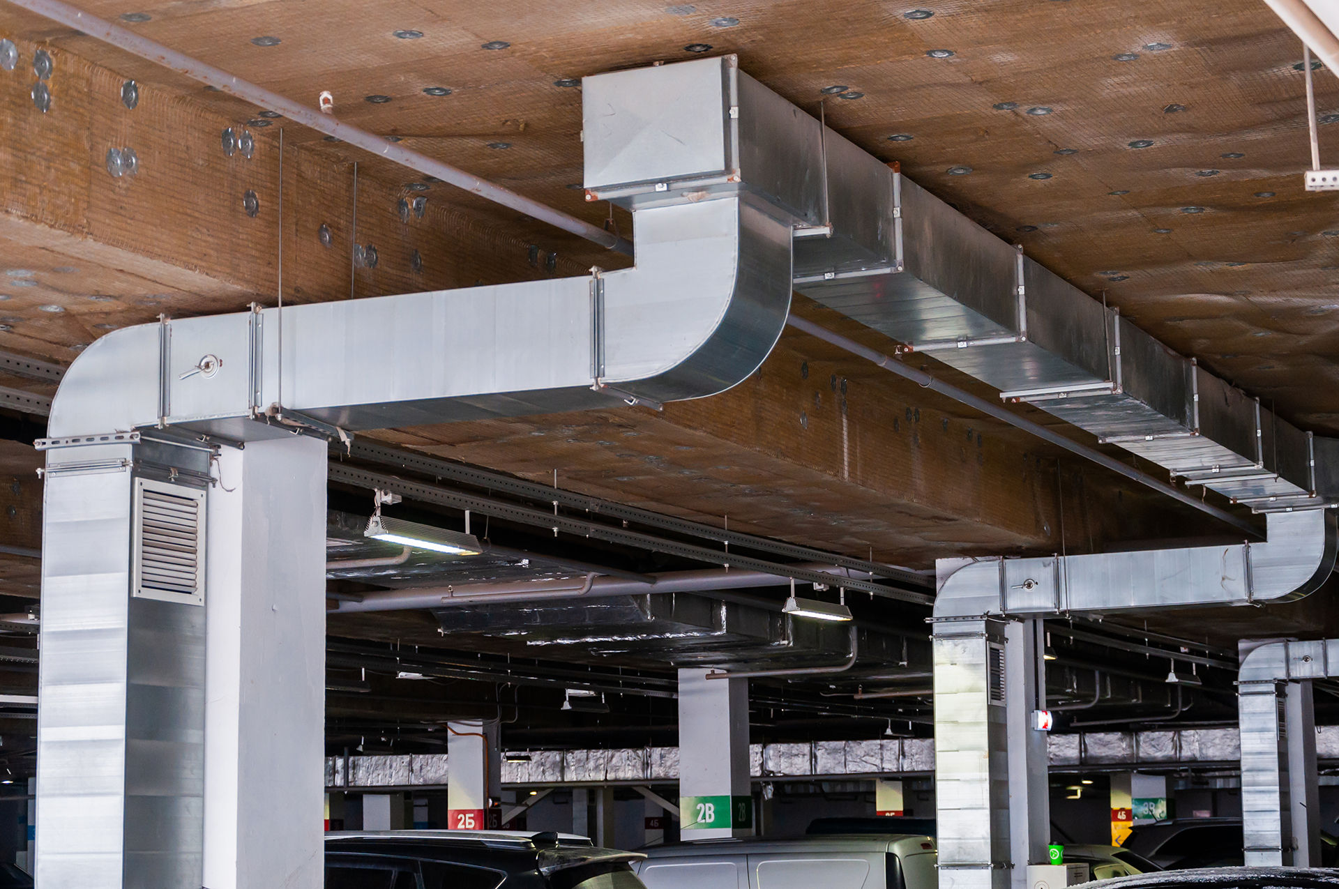 Integrated car park ventilation and smoke control system installed within an underground commercial car park, featuring mechanical exhaust ductwork, ventilation grilles, axial fans, and engineered airflow systems designed to support occupant safety, air quality, and emergency smoke management. These systems are commonly integrated with Carbon Monoxide (CO) monitoring, Variable Speed Drives (VSDs), fire systems, and Building Management Systems (BMS) to comply with AS1668.2 requirements while improving operational control, energy efficiency, and fault monitoring across commercial buildings in Melbourne, Sydney, and Canberra.