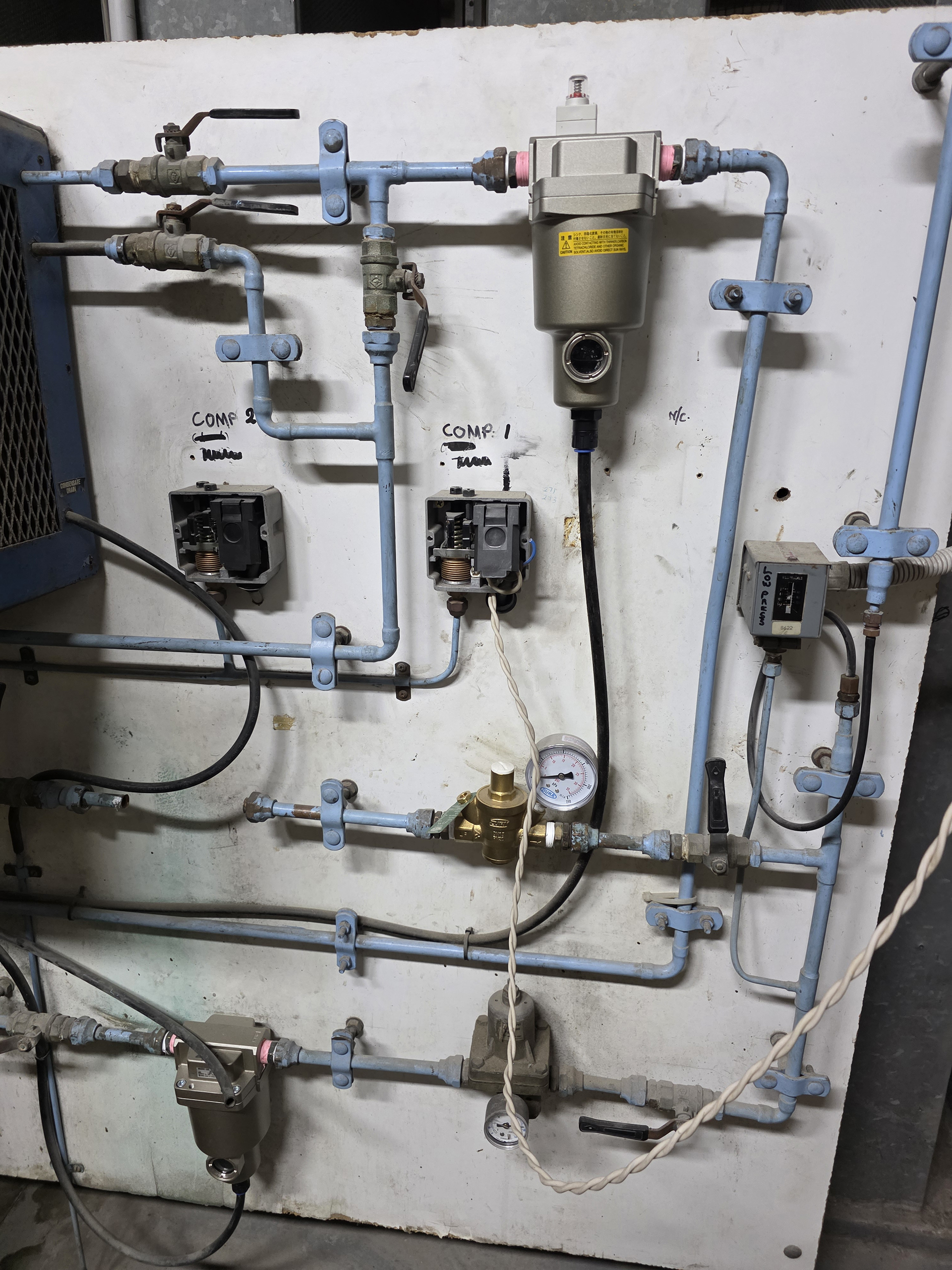 Commercial HVAC pneumatic control air station with filters, regulators, gauges, and pressure switches supplying compressed air to building control systems.