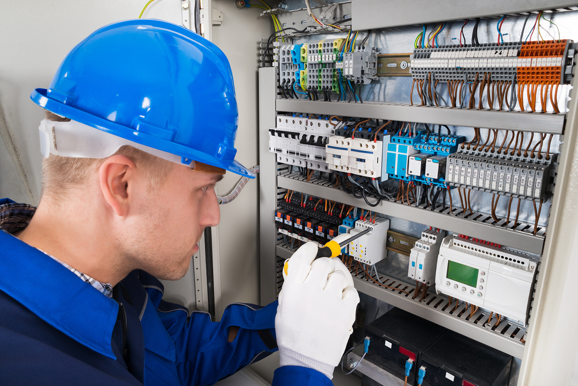 Engineer inspecting a commercial Building Management System control panel to assess its condition, documentation and suitability for upgrade or replacement.