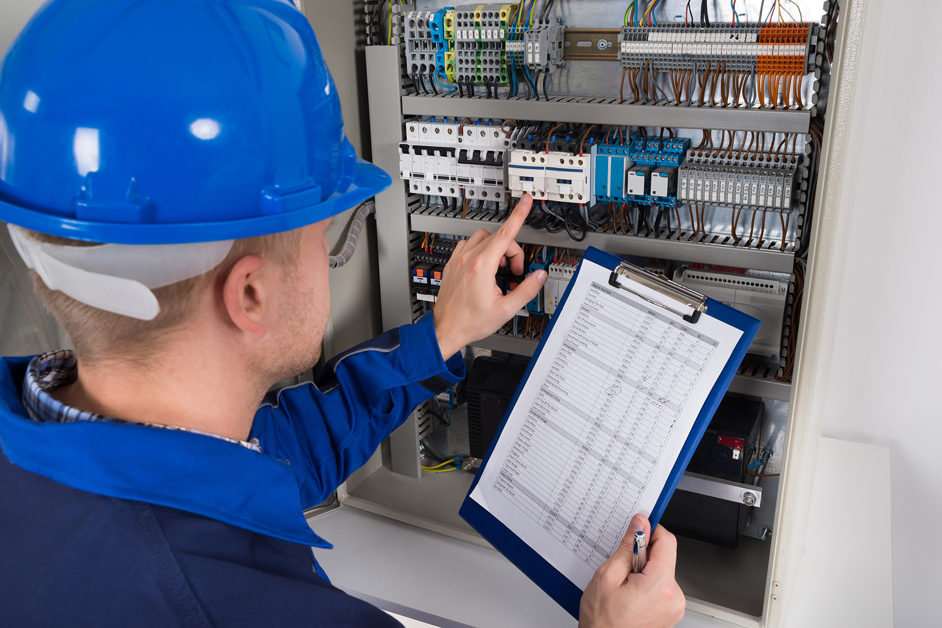 Technician wiring a Building Management System control panel while commissioning field devices and verifying the BMS Points List for commercial HVAC controls.