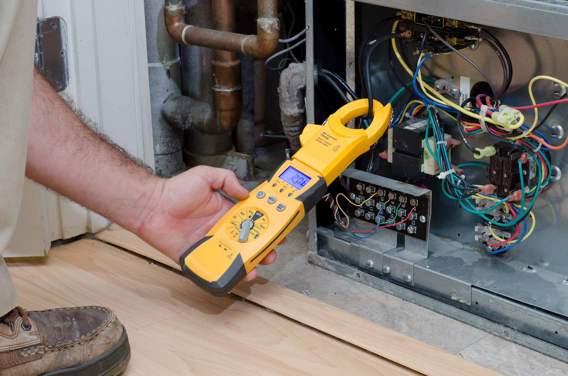wr8Technicain working with a current meter inviesting a pckage unit on a roof top for commissioning