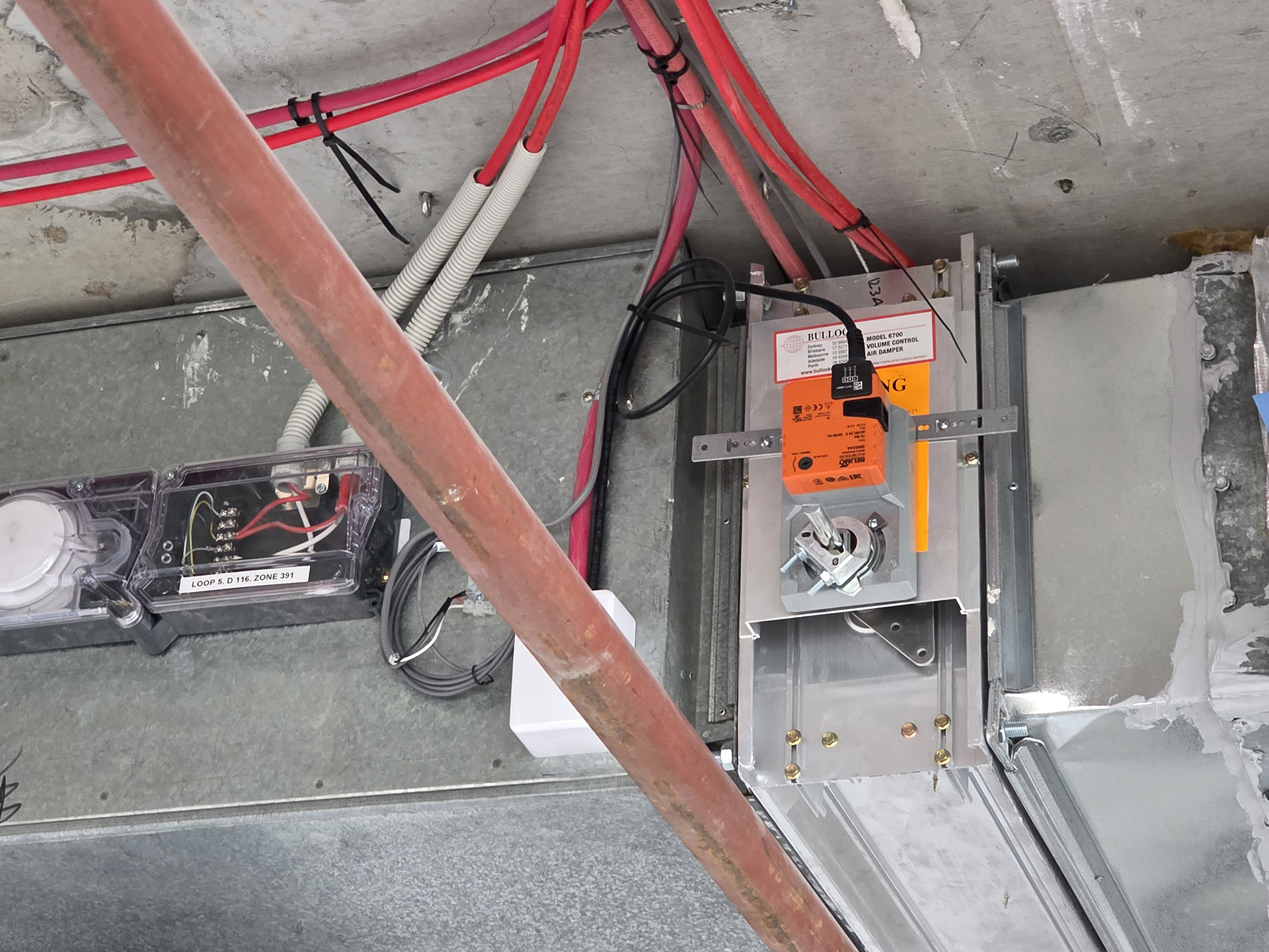 Commercial HVAC supply air duct fitted with a Belimo spring-return fire damper actuator and duct smoke detector used to isolate air conditioning systems during a building fire emergency.