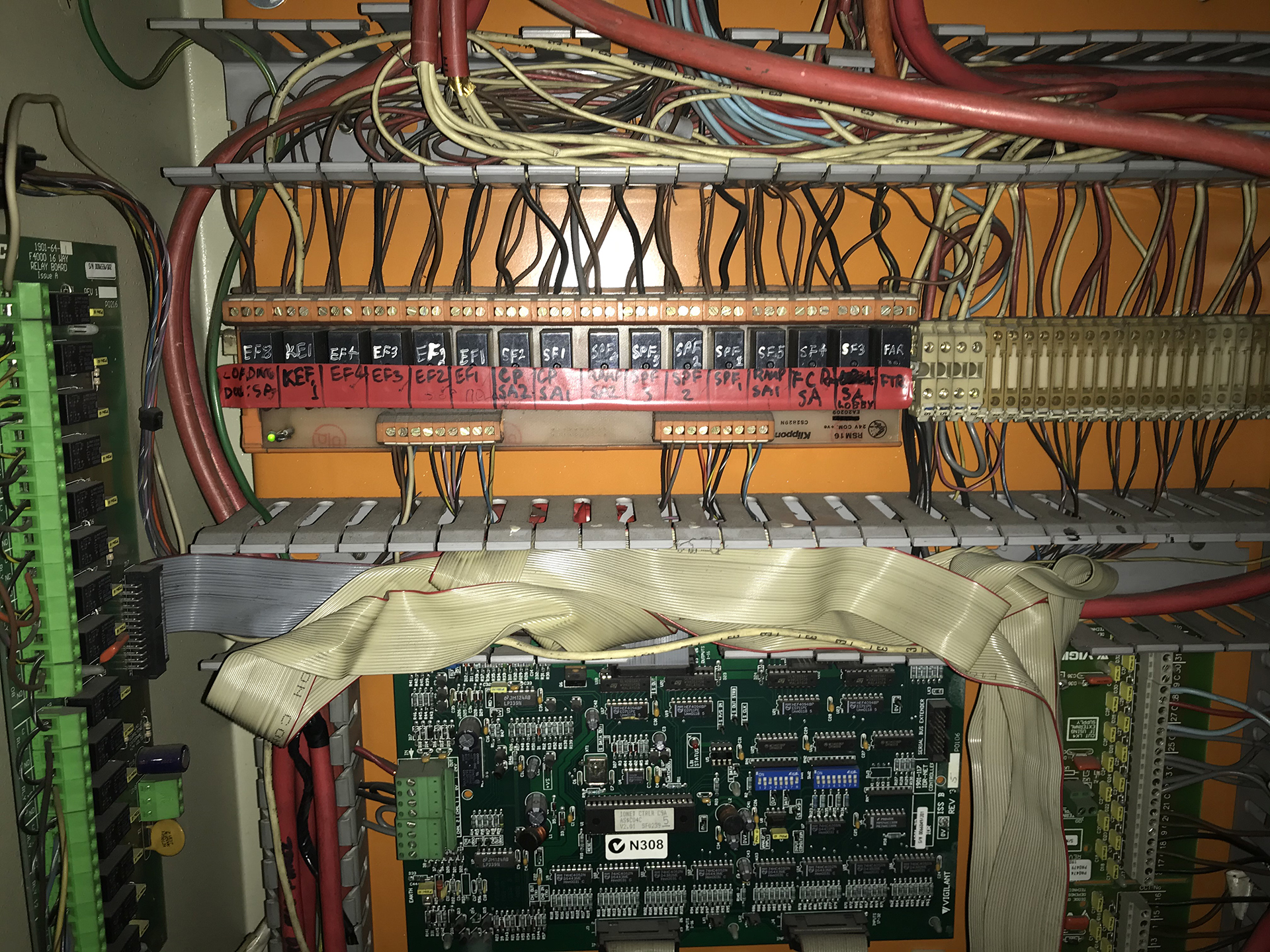 Large, obsolete BMS motherboard connected to control modules by ageing ribbon cables inside a mechanical services panel.
