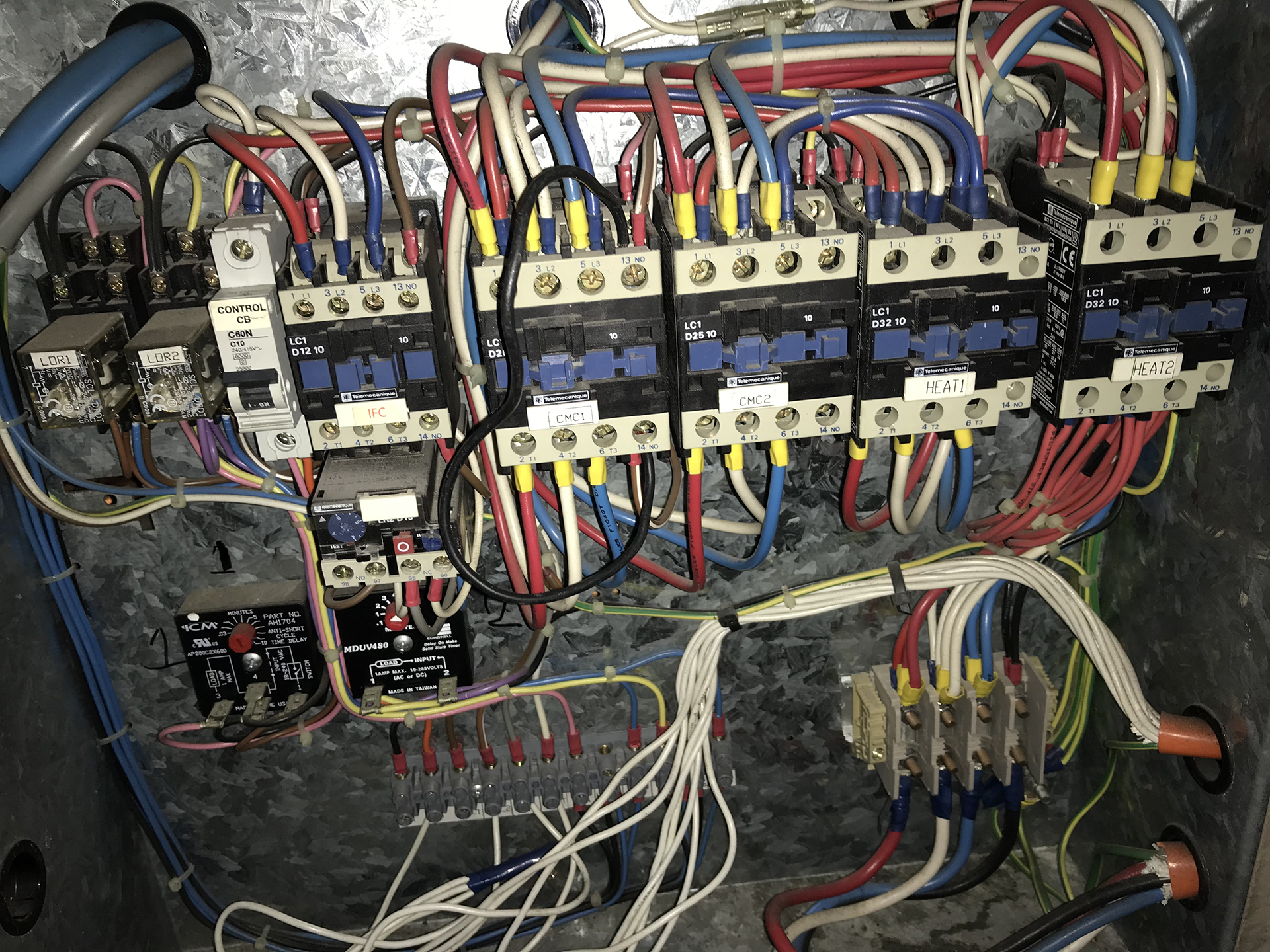 Electrical contactors, relays and control wiring inside a commercial rooftop packaged air-conditioning unit inspected during BMS recommissioning.