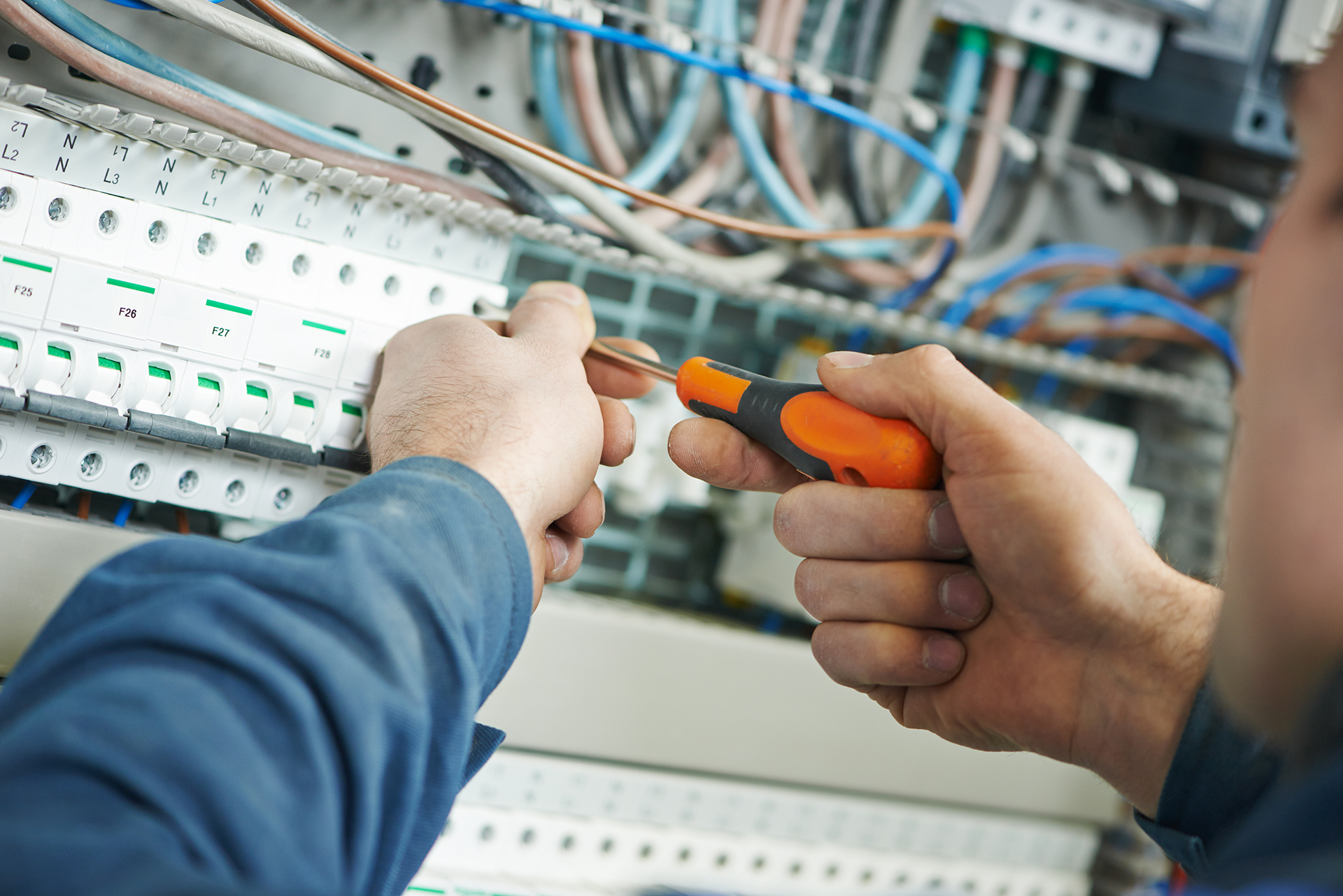 Electrician carrying out refurbishment work inside a mechanical services switchboard with modern circuit protection and wiring.