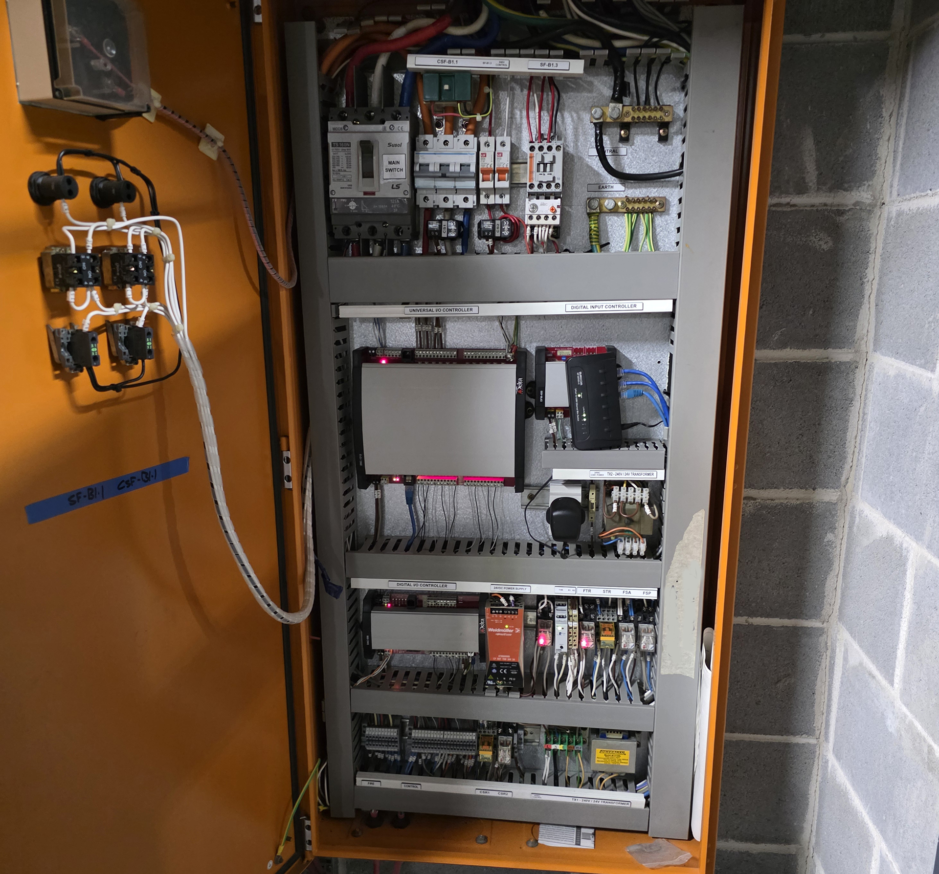 Overcrowded mechanical services switchboard containing an obsolete BMS controller, added network equipment and limited space for further modifications.